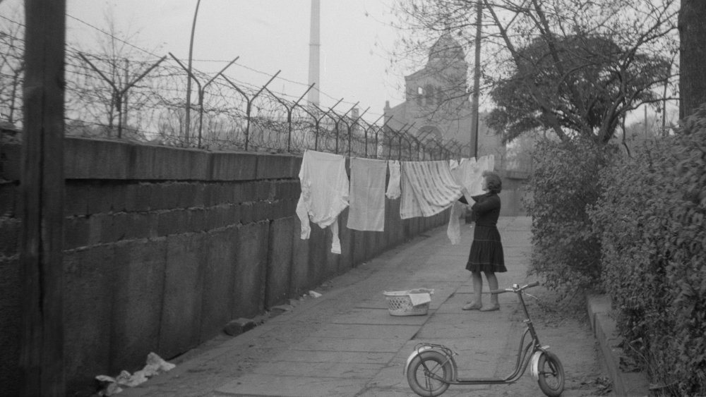 A woman hangs laundry near the Berlin Wall
