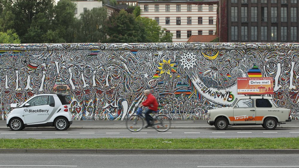 A woman rides her bike by the remains of the Berlin Wall