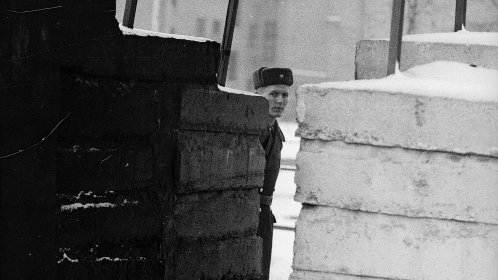 A patrolman peeks through the Berlin Wall