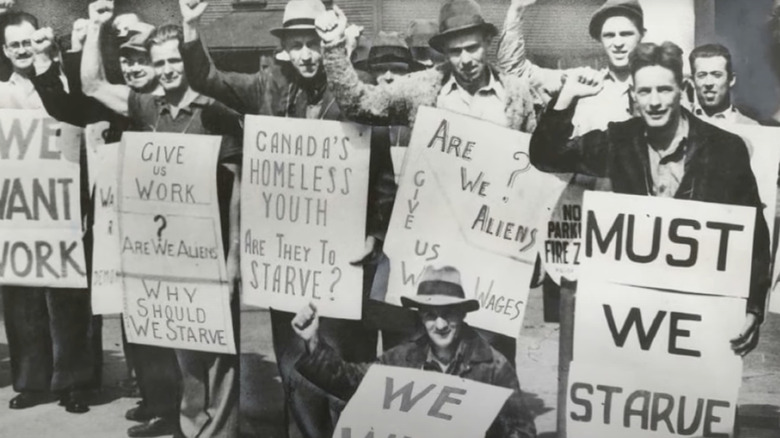 Men holding signs demanding work in Canada