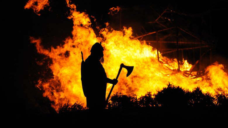 man with battle axe in front of fire