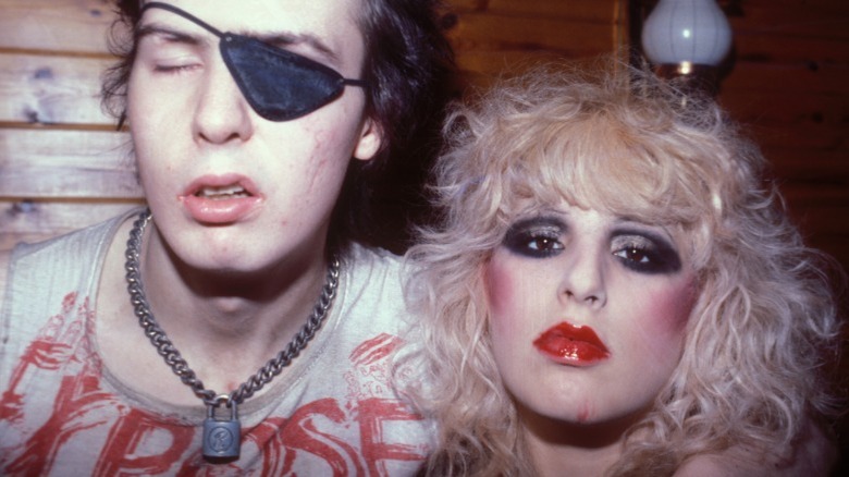  Nancy Spungen wearing heavy makeup and posing with Sid Vicious wearing an eyepatch