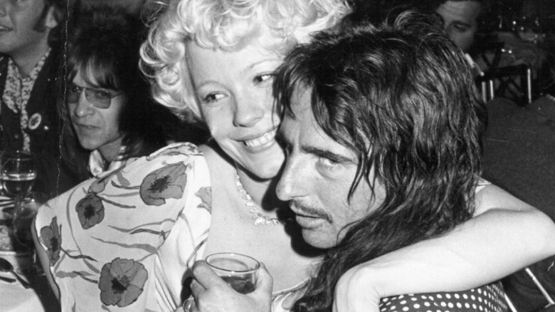 Black and white photo of Pamela Des Barres smiling with her arm around Alice Cooper