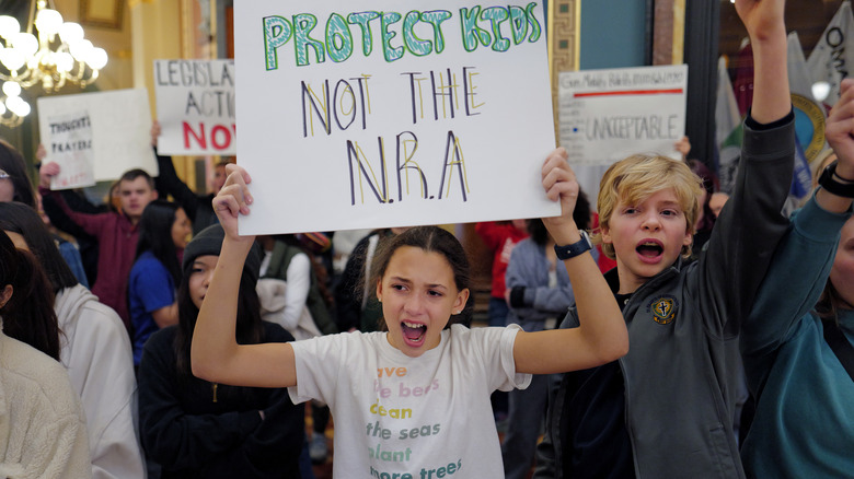 student holding a sign saying protect kids not the NRA