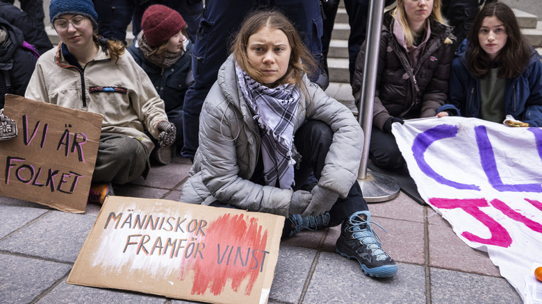 Greta Thunberg sitting on the sidewalk