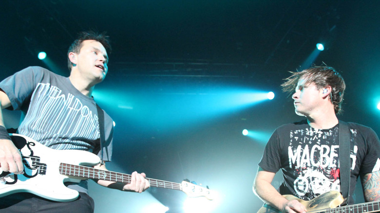 Blink-182 on stage posing with guitars blue backlit