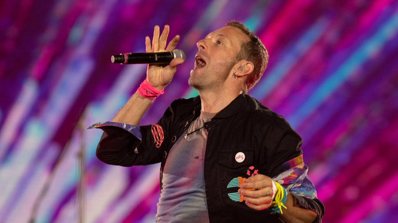 Chris Martin on stage singing purple sparks background