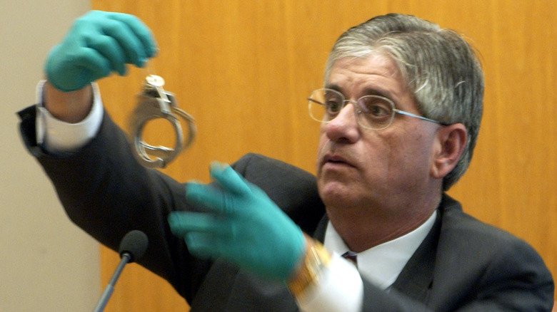 Ken Landwehr holding up a pair of handcuffs in court