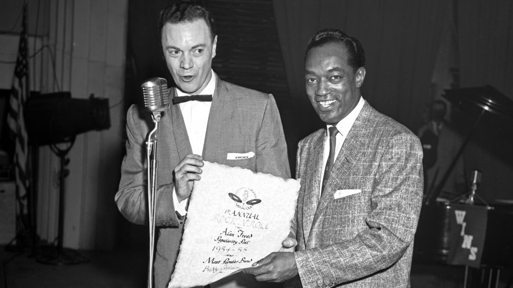 Rock and roll disc jockey Alan Freed presents band leader Buddy Johnson with a certificate that reads "1st Annual Rock and Roll Alan Freed Popularity Poll. 1954-55. Most Popular Band. Buddy Johnson" at his WINS Rock and Roll Party show at St. Nicholas Arena on January 14, 1955 in New York, New York.