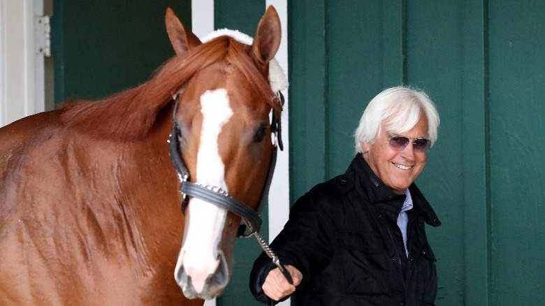 Bob Baffert smiling while leading a horse