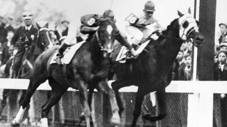 Black and white photo of two jockeys fighting while on horses