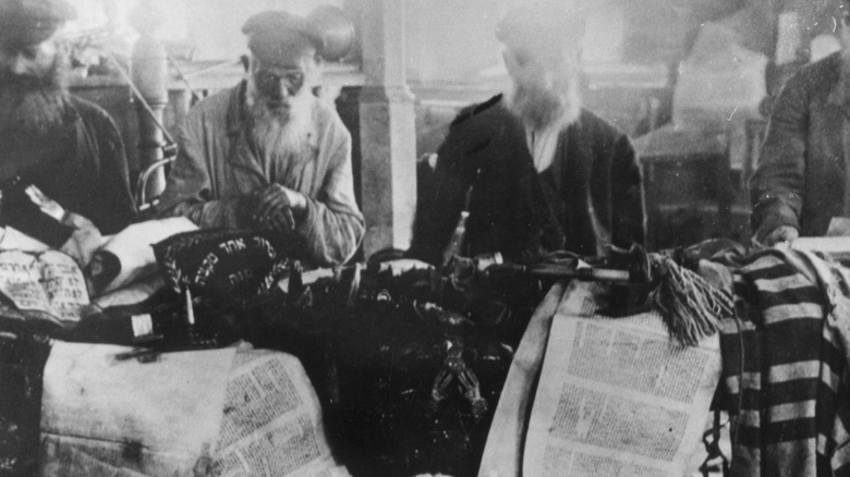 men looking at desecrated Torah scrolls 