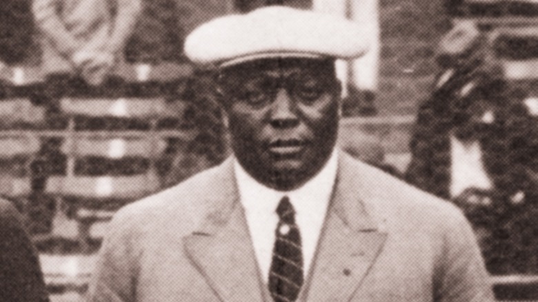 Suited Rube Foster standing, looking forward in flatcap