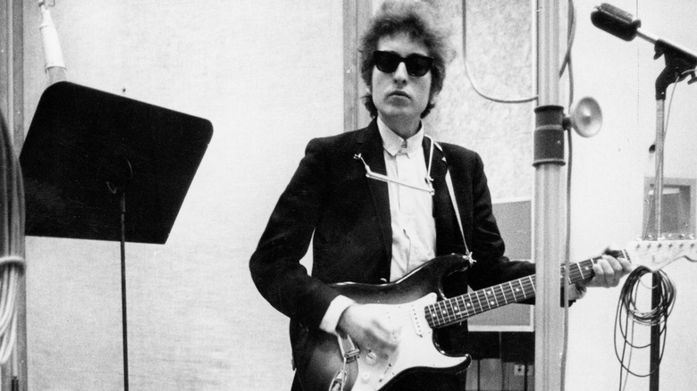 Bob Dylan sunglasses suit posing with a Stratocaster