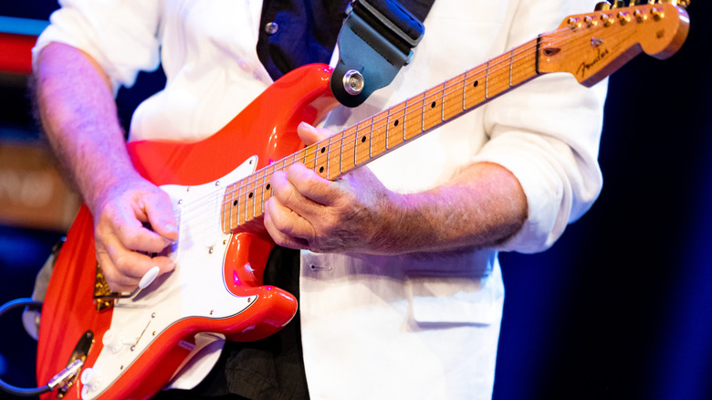 Guitarist white suit playing a red Stratocaster