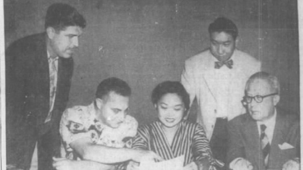 Newspaper clipping of photo of Patsy Mink sitting and looking at a document 