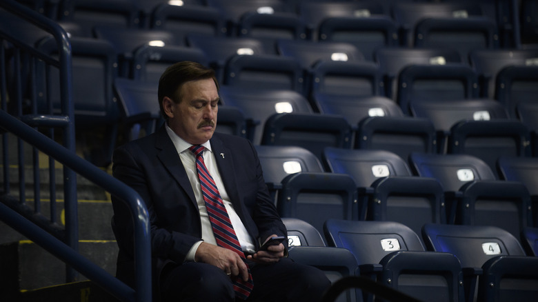Mike Lindell sitting alone looking at his phone