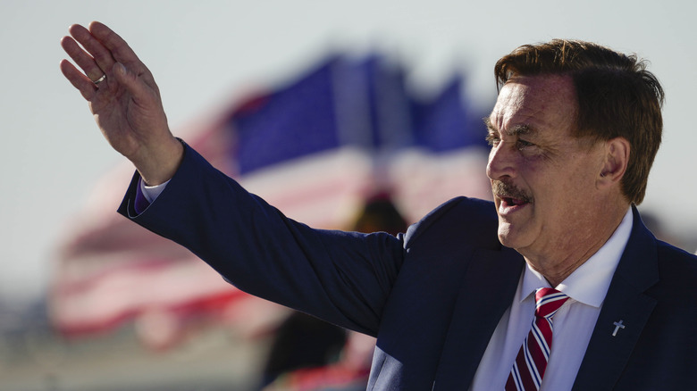 Mike Lindell waving in front of flags