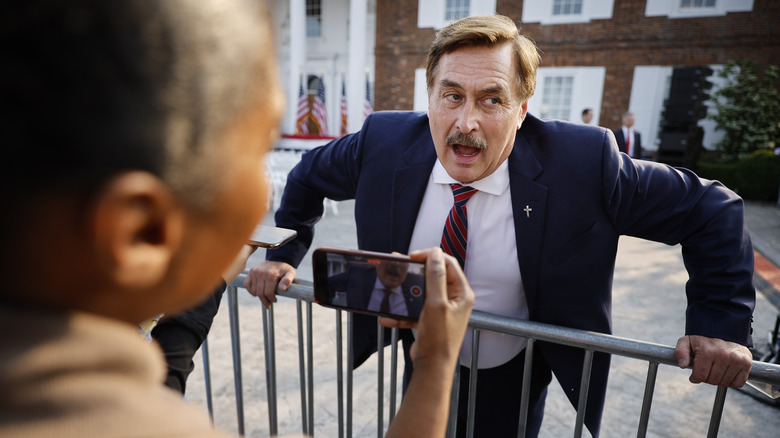 Mike Lindell leaning on a fence talking