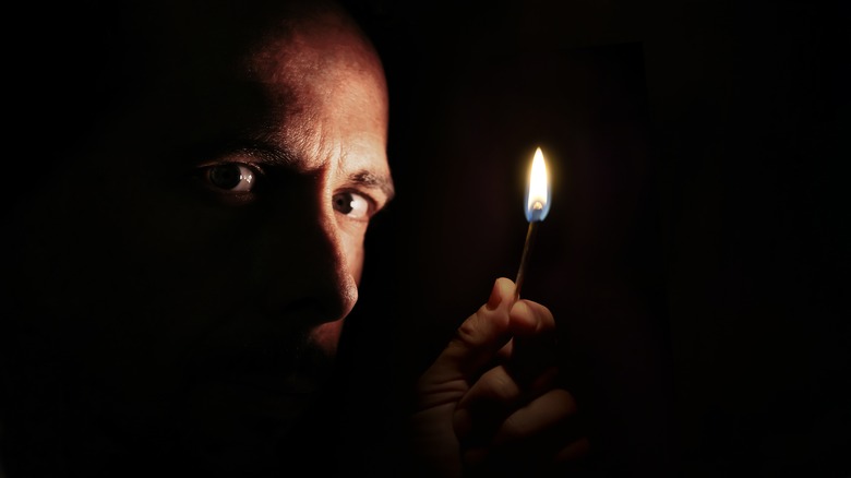 Man with lit match in dark