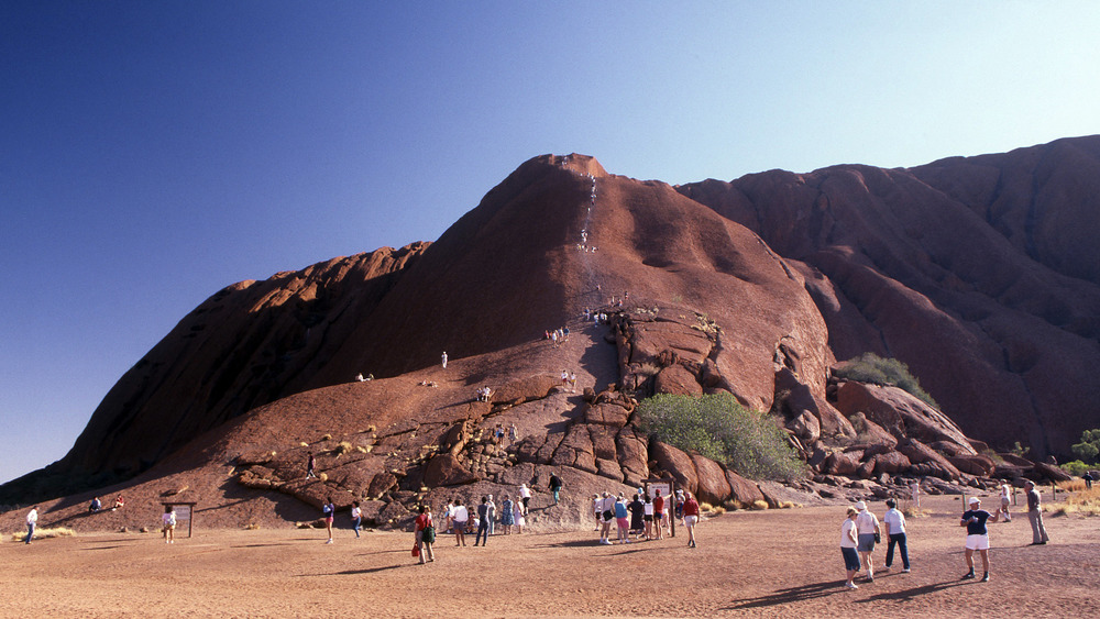 tourists climbing ayers rock