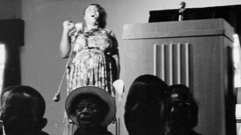 Fannie Lou Hamer standing beside a podium, microphone in front of her