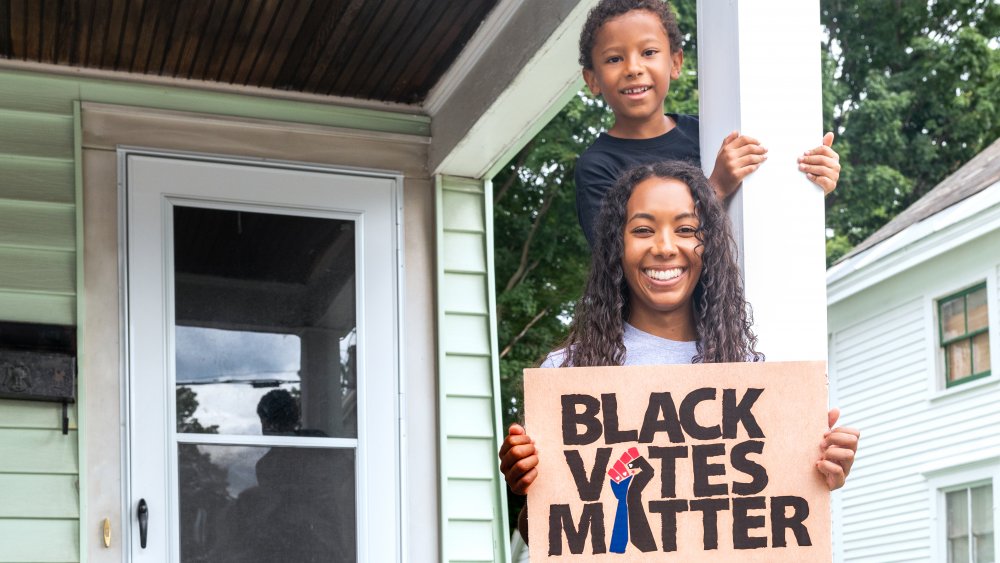 Mother and son holding sign that says Black Votes Matter