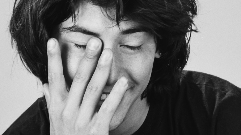 a very young keanu reeves with hand on face