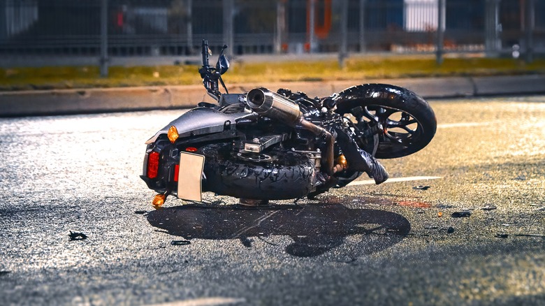 Wrecked black motorcycle lying on highway