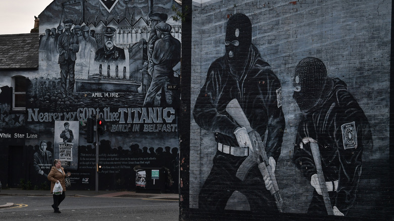 Woman walks past black-and-white mural with gunmen