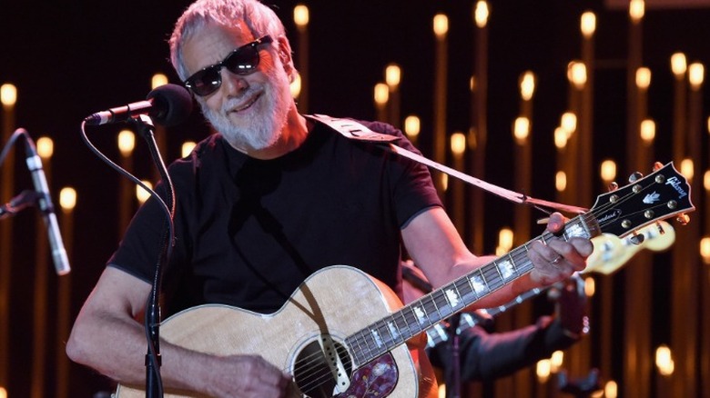 Cat Stevens smiling and playing the guitar in 2019