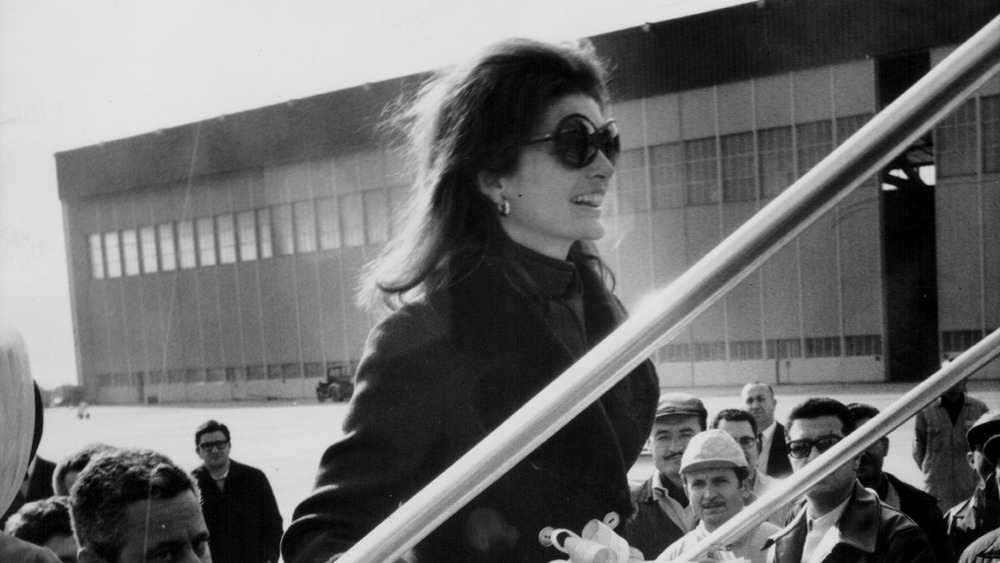 Jacqueline Kennedy Onassis walking up steps to board a plane
