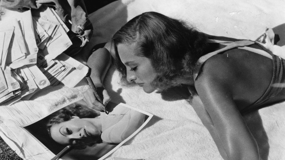 Joan Crawford lounging and signing autographs