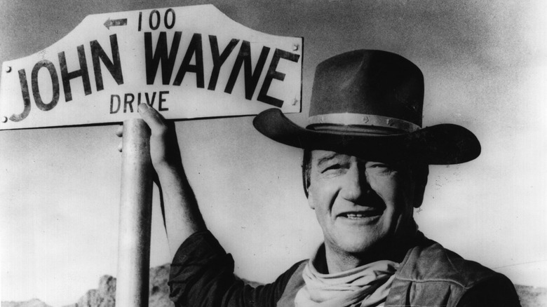 John Wayne holding a sign with his name on it