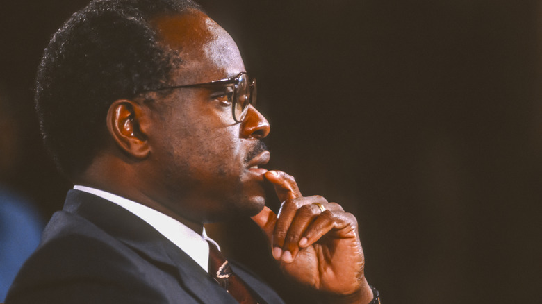 A red-eyed Clarence Thomas with hand to mouth