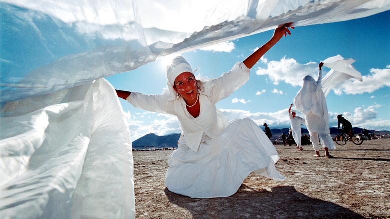 Women white dress face paint dancing desert