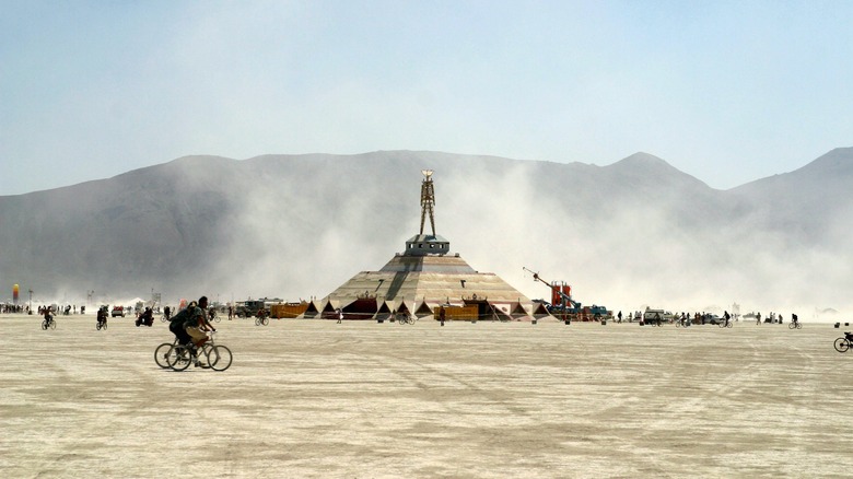 People riding bikes Burning Man effigy desert