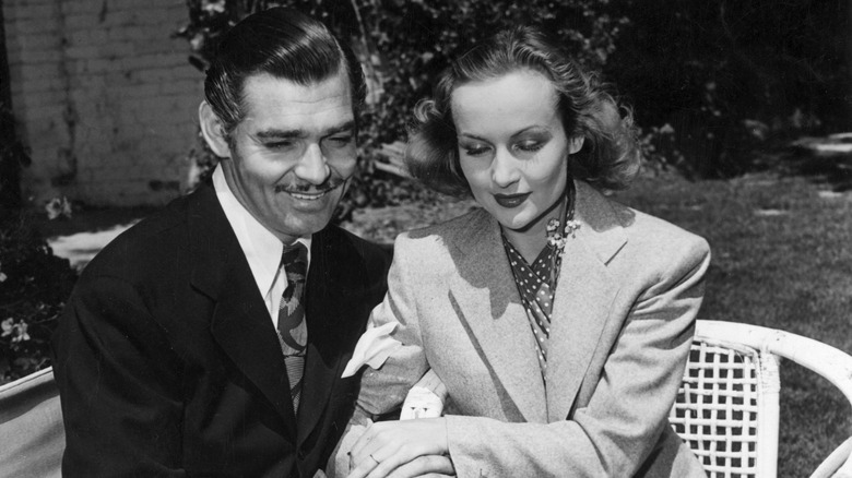 Clark Gable and Carole Lombard sitting, holding hands