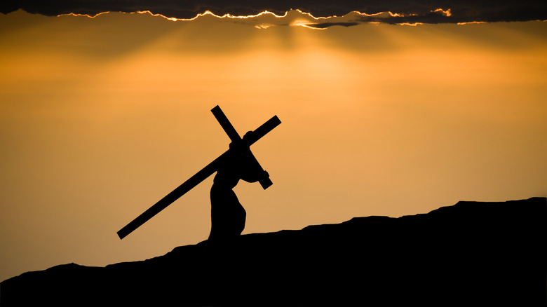 silhouetted figure carrying cross
