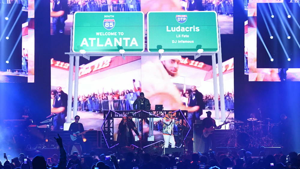 Ludacris, Lil Fate, and DJ Famous performing on a stage with "Welcome to Atlanta" signs