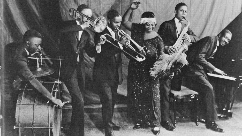 1924: "Mother of the Blues" Ma Rainey and her band the Rabbit Foot Minstrels with Ed Pollock, Albert Wynn, Thomas A. Dorsey (on piano at right) Ma (Gertrude) Rainey, Dave Nelson and Gabriel Washington pose for a portrait circa 1924 in Chicago, Illinois. 