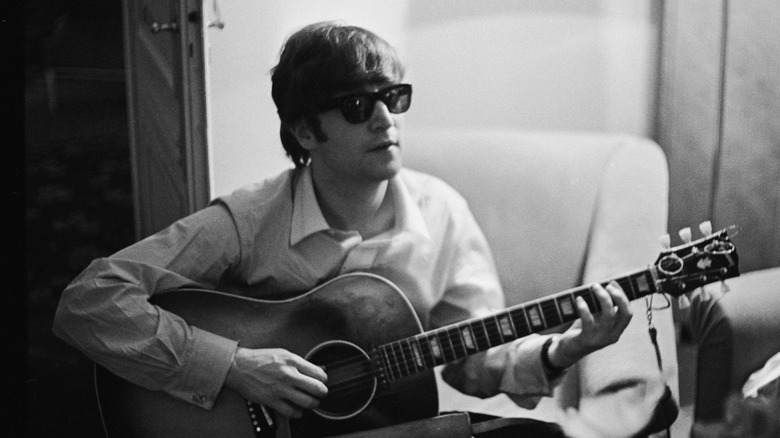John Lennon wearing sunglasses playing a guitar