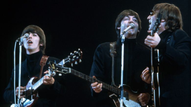 George Harrison, Paul McCartney, and John Lennon performing onstage