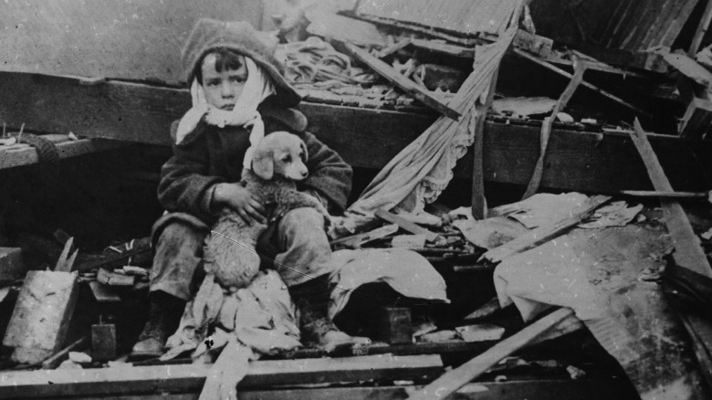 Boy and his puppy sit in the wreckage of a hurricane in the 1920s, black and white
