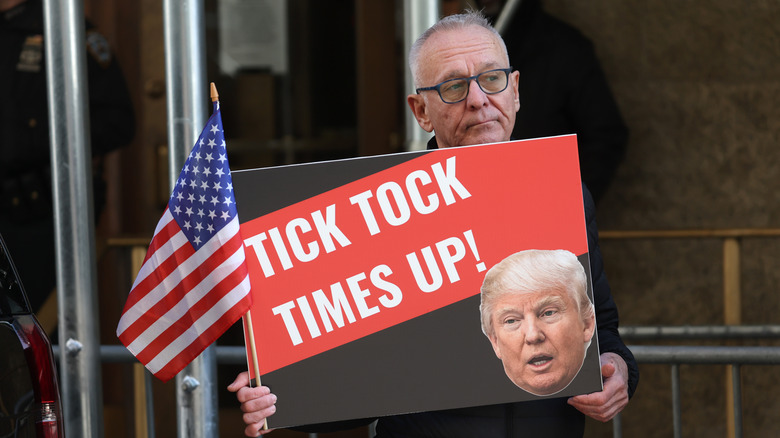 Protestor with "times up" sign featuring Trump