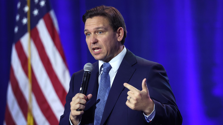 Ron DeSantis gesturing while speaking in front of an American flag