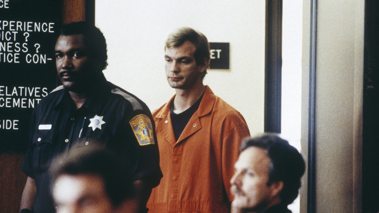 Jeffrey Dahmer in orange jumpsuit, escorted by police