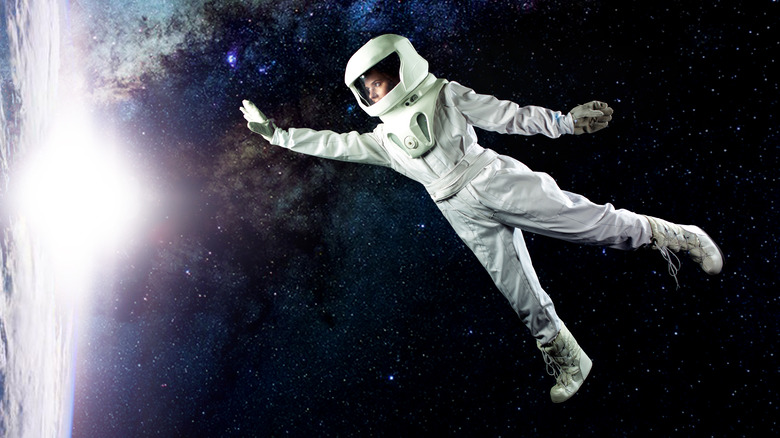 floating astronaut reaching out in space