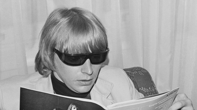 Keith Relf in sunglasses looking at book