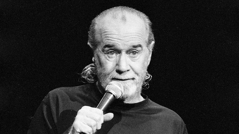 George Carlin on stage with microphone